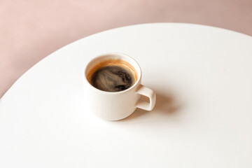 Black strong coffee in a white cup on a round table. Minimalistic banner hot Americano with space for text. The perfect mockup for advertising coffee