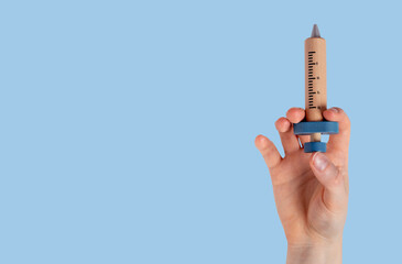Hand with wood toy syringe on blue medical ad banner with copy space for text. High quality photo