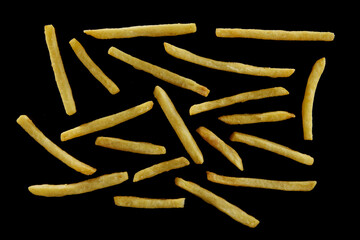 Sticks of delicious French fries placed on black surface