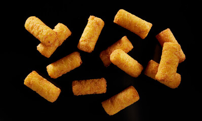 Yummy breaded mozzarella sticks against black background