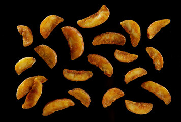 Appetizing potato wedges on black background