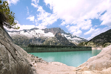 Alps mountains beautiful landscape with turquoise water lake and scenic mugs pine. High mountains nature and view on dam of Gelmer lake reservoir , sunny summer day.