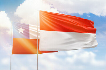 Sunny blue sky and flags of indonesia and chile