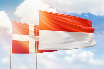 Sunny blue sky and flags of indonesia and denmark