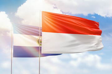 Fototapeta na wymiar Sunny blue sky and flags of indonesia and el salvador
