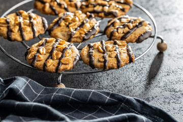 Chip cookies with peanuts and chocolate strips on black table.