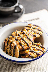 Chip cookies with peanuts and chocolate strips in bowl.