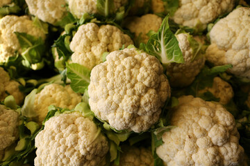 Fresh harvested cauliflowers on grocery shelf together.