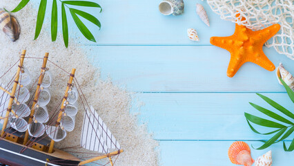 On a blue wooden background, shells, sand, ship model