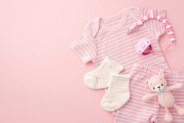 Baby accessories concept. Top view photo of pink infant clothes shirt shorts socks knitted teddy-bear toy and pacifier chain on isolated pastel pink background