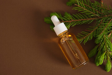 glass dropper bottle with cosmetic serum or oil and sprig of spruce with fresh shoots, young shoots...