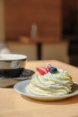 meringue cake with buttercream and fresh strawberries on top. Cupcake dessert and coffee in cafe.
