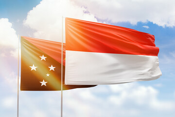 Sunny blue sky and flags of indonesia and papua new guinea
