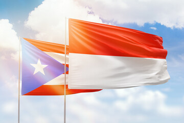 Sunny blue sky and flags of indonesia and puerto rico