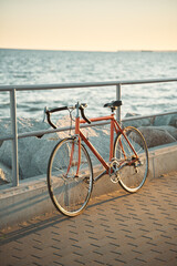 Orange vintage road bicycle. Closeup of a bike on the seaside during a summer evening. Old cycle restored.