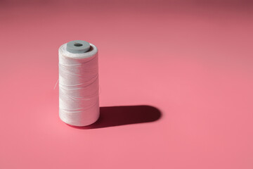 spool of white threads on a colored background with copy space