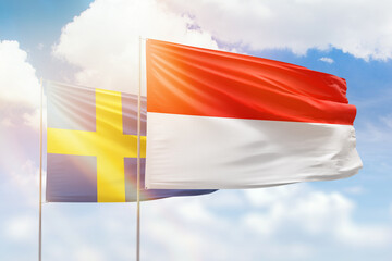 Sunny blue sky and flags of indonesia and sweden