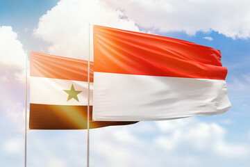 Sunny blue sky and flags of indonesia and syria
