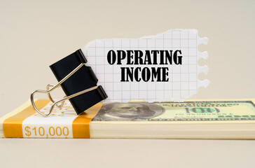 There are dollars on the table, on which there is a clip and torn paper with the inscription - OPERATING INCOME