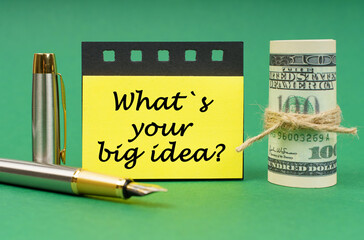 On a green surface, a pen, dollars, a notepad and yellow stickers with the inscription - What is...