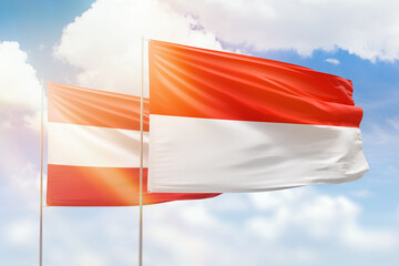 Sunny blue sky and flags of indonesia and austria