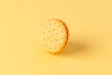 Minimalism. Cookies with fruit filling on a yellow background stand on the edge. Two cream cookies with fruit filling between them on a yellow background. Light background. Close-up. Side view