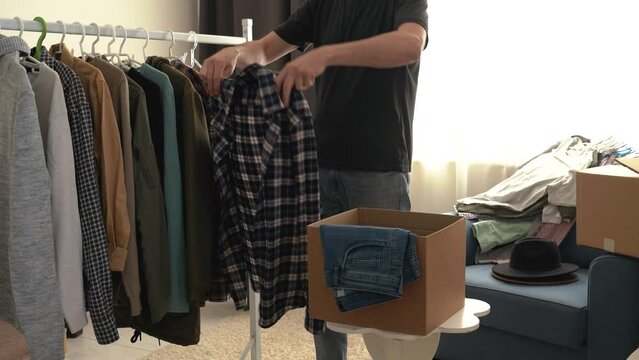 No face. Wardrobe ore closet for man sorting clothes for charity in donate box during cleanup at walk-in closet. Home routine. housework. He changes clothes from winter to summer. 4k