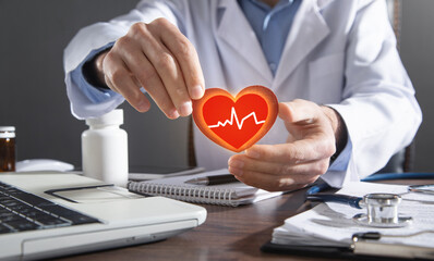 Doctor holding red heart with cardiogram.