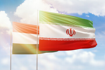 Sunny blue sky and flags of iran and hungary