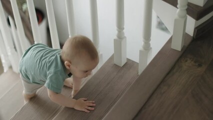 baby toddler boy climbing crawling upstairs home indoors learning to climb stairs. child kid using barefoot legs, tiny hands, going up wooden steps and stair. safety children concept