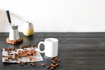 White espresso cup, mug, chocolate, coffee beans on kitchen table, utensils dishware, coffee pot on black wooden shelf. morning french home hot beverage breakfast, mock up, copy space