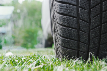 Fototapeta na wymiar Car tire on the green grass. Winter car tire on the grass