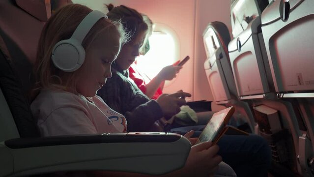 Family of mother and two kids with gadgets in the plane