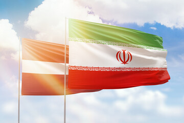 Sunny blue sky and flags of iran and latvia