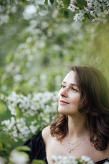 Fototapeta premium young woman in a park with flowering trees, beauty portrait.