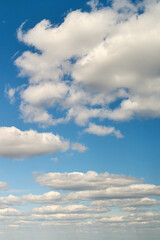 White cumulus clouds in the blue sky. Bright beautiful sky, copy space background