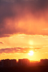 Dark clouds in the evening sunset sky with the setting sun. Dramatic sky during orange sunset