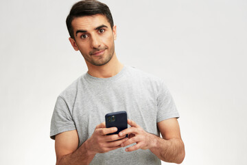 Cheerful man in a gray t-shirt with a phone communication technology cropped view