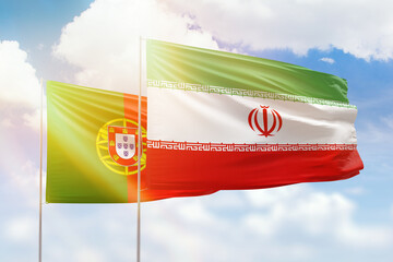 Sunny blue sky and flags of iran and portugal