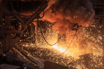 Hot red melting slag is pouring from blast furnace tap hole.