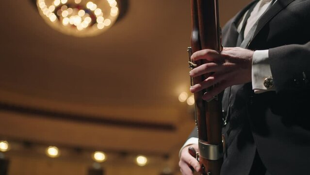adult man in concert suit is playing bassoon on scene of old opera theater, musician and symphony
