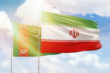 Sunny blue sky and flags of iran and turkmenistan