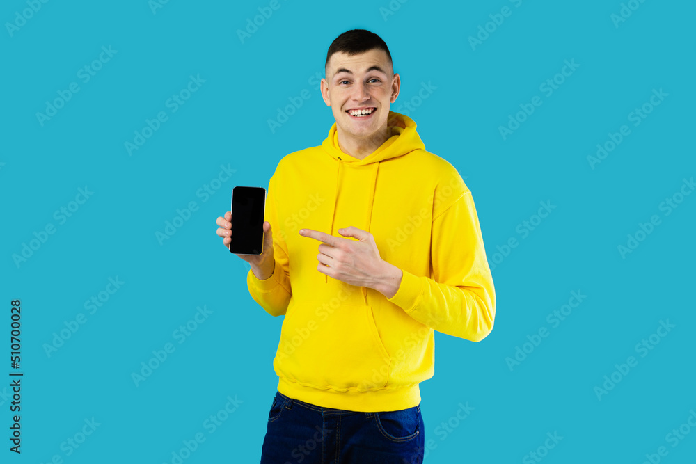 Poster guy showing smartphone pointing at blank screen over blue background