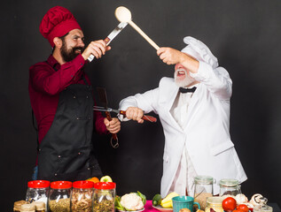 Two restaurant chefs or bakers in uniform fighting in kitchen. Cooking food. Competition of chef.