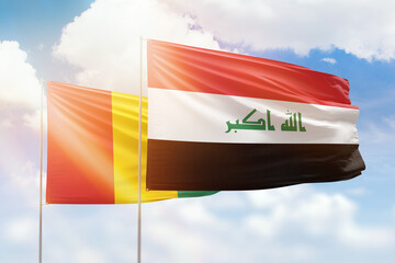 Sunny blue sky and flags of iraq and guinea