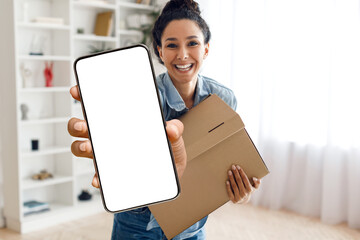 Delivery App. Smiling young woman with parcel showing smartphone with blank screen