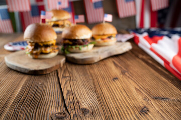 Fourth of July celebration. American flag and decorations. Burgers on rustic wooden table.