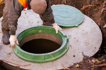 the builder installs a manhole on a concrete sewer well. Construction of a septic tank for a country house