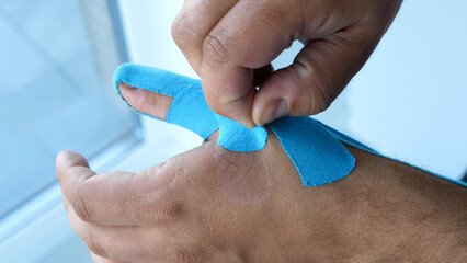 Man taking kinesiology tape off his thumb