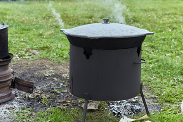 Hiking pot, Bowler in the bonfire. in cauldron at the stake. Traveling, tourism, picnic cooking,...